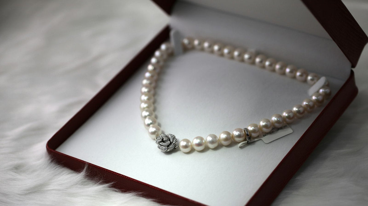 Pearl strand necklace with a pavé flower clasp in an open red jewelry box