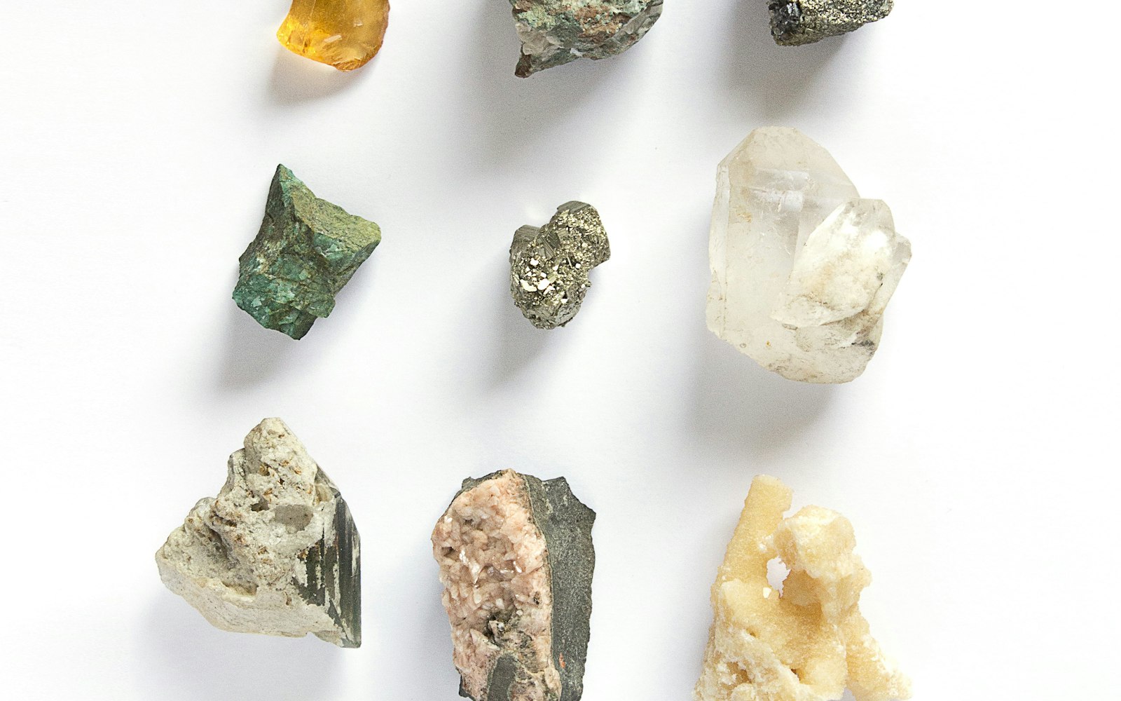 Assortment of rough, uncut gemstones in different colors arranged on a white surface